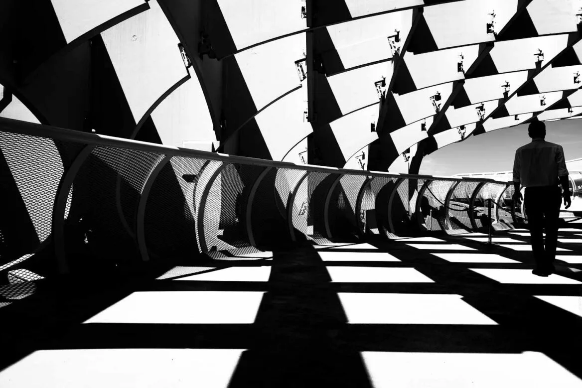 sunlight flowing through structure creating distinctive shadows as a stranger walks away